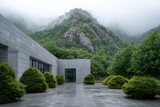 Modern building with a stone plaza set against a backdrop of misty mountains and lush greenery