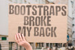 © AndriiKoval - 'Bootstraps Broke My Back' critiques individualist myths of success, highlighting the real cost of systemic inequality.FUTILITY. IRONY. CAPITALISM. RESISTANCE. STRAIN. MOCKERY. STRUGGLE.