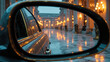 © Designbd25 - Car side mirror reflecting a wet street with golden lights and a building with columns during a rainy evening