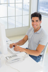 Man typing on keyboard at office desk using computer monitor and telephone, copy space