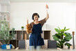 © Natee Meepian - Home Cleaning. Excited woman celebrating while cleaning, showcasing joy in household tasks.