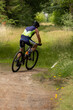 © MZandt - Mountain biker takes a turn and participates in a cycling race during an event in the forest, sporting activity
