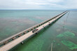 © AmazingAerialAgency - Aerial view of a truck traversing the iconic Seven Mile Bridge as turquoise waters meet the sky, creating a stunning contrast of colors, Big Pine Key, Florida, United States.