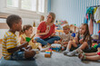 © lordn - Preschool teacher leading a music lesson, engaging children in rhythm and percussion activities during group playtime.