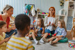© lordn - Preschool teacher leading a music lesson, engaging children in rhythm and percussion activities during group playtime.