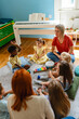 © lordn - Preschool teacher leading a music lesson, engaging children in rhythm and percussion activities during group playtime.