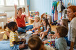 © lordn - Preschool teacher leading a music lesson, engaging children in rhythm and percussion activities during group playtime