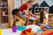 © lordn - Preschool children eating fresh watermelon slices at table, enjoying healthy snack in bright classroom