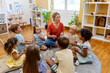 © lordn - Preschool teacher engaging a group of children in a fun music activity, sitting in a circle and playing rhythm instruments in a bright classroom