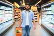© Serhii - Indian man walking through supermarket aisles carrying shopping basket