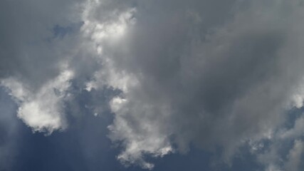 Wall Mural - Time-lapse of grey smoky looking clouds churning and moving with the sun lighting the edges of a few clouds timelapse
