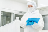 水工場,飲料メーカーで働くペットボトルの水をチェックする防塵服姿の製造スタッフ（飲料メーカー）
