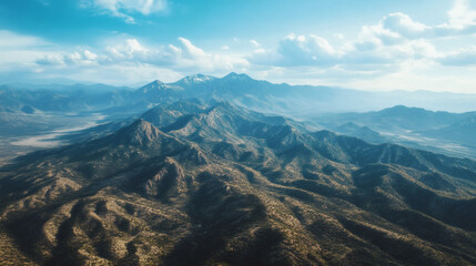 High angle view of a rugged mountain range under a partly cloudy sky.