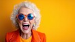 © senadlife - This cheerful elderly woman radiates happiness with her bright orange outfit and playful blue sunglasses, portraying the essence of joy and vibrancy in aging gracefully.
