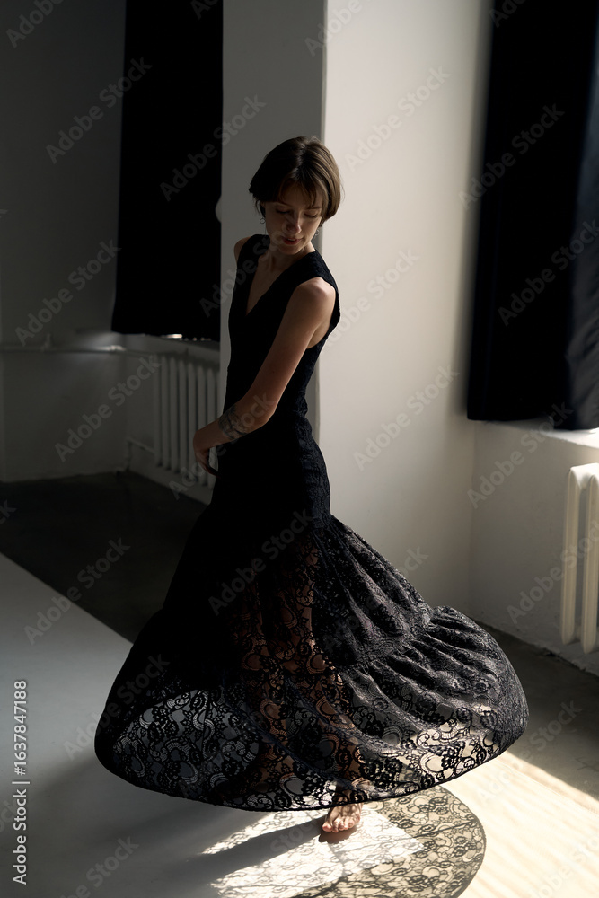 Fashion model in black evening dress creates dynamic pose against ...
