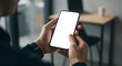 © ekam - Close-up of a man's hands holding a smartphone with a blank white screen in a modern office setting
