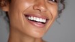 © Johannes - close up face of young woman with beautiful smile isolated on grey wall with copy space successful multiethnic girl latin woman looking at camera against gray wall with a big whitening teeth smile no