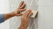© moo - Man hangs wallpaper on wall, using tool. Home improvement and renovation project. Worker installing modern decorative wall covering.