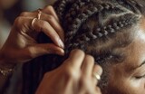 Hairdresser braiding client's hair in salon: close-up of hands working on intricate braids