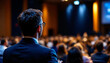 © Zabed - A man in a suit and tie stands confidently before an engaged crowd, delivering a speech or presentation.
