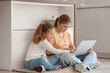 © Pixel-Shot - Cute sisters watching cartoons on laptop in kitchen