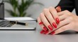 © image stock - Business woman with red manicure at desk with laptop and pen