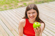 © luismolinero - Young pretty woman at outdoors holding an apple with happy expression