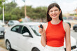 © luismolinero - Young pretty Ukrainian woman holding car keys at outdoors smiling a lot