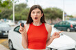 © luismolinero - Young pretty Ukrainian woman holding car keys at outdoors surprised and pointing side