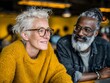 © CHAIYAPHON - A mature woman with glasses smiles while sitting next to a man with a beard in a casual setting.