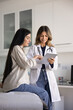 © fizkes - Positive Latin healthcare professional woman talking to patient, using tablet for showing medical report, checkup result, explaining diagnosis. Female Hispanic doc giving consultation. Vertical shot