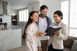 © fizkes - Couple reviewing mortgage or real estate documents during meeting with Indian woman agent, examining lease agreement and legal papers related to purchasing or renting property, learn insurance policy