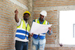 © krongthip - A young male engineer carries structural blueprints and a laptop while inspecting work at the construction site.
