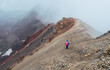 © Soloviova Liudmyla - Lonely female backpacker dressed rain cover with backpack and trekking poles making acclimatization trek around Lenin peak base camp climbing Petrovsky Peak 4910 m, Pamir mountains range, Kyrgyzstan.
