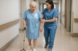 © Татьяна Евдокимова - Nurse providing careful assistance to elderly female patient using a cane while walking through a hospital corridor, ensuring safe movement