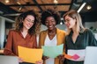 © Octopus - Three cheerful women are reviewing colorful documents together in a bright office space creating a positive atmosphere for teamwork