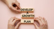 © Loka Design - Close-up of hands holding a wooden block reading develop a growth plan perfect for business strategy personal development and success motivation themes