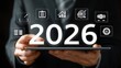 © Gilang - Businessman displays 2026 on tablet with icons