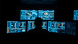 © MdShahajan - Silhouette of a person in front of multiple glowing computer screens displaying data