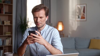Young man in headphones typing on laptop at home checking email sending message browsing social network chatting making order in online store mature businessman freelancer working on internet