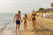 © BGStock72 - Family enjoys a joyful stroll along the beach during sunset on a warm evening