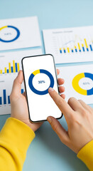 Wall Mural - hands hold smartphone displaying blue and yellow pie chart, 30% highlighted. background shows busine