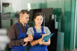 © JackF - Glass factory employees, young adult woman and man in blue overalls reviewing quality check results on clipboard while standing in workshop