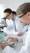 © rogerphoto - Medical researchers, male and female, examining laboratory samples under microscope and digital tablet during joint scientific research. Medicine and science, teamwork concept