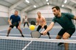 © Jafree - Group of adults playing pickleball on indoor court with competitive spirit and focus. concept of team sport, active lifestyle, recreational fun