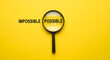 © creative - Magnifier focuses on the possible side of the word impossible.