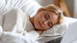 © 沈军 贡 - A young woman sleeps comfortably on a white bed with a laptop nearby, appearing relaxed and at peace in a cozy indoor setting.