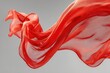 © Nanda - Bright red sheer fabric gently flows on a gray studio background. This image can add vibrant elegance to creative projects or marketing.