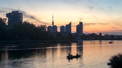 Wall Mural - scenic view of vienna skyline at sunset with reflections on the danube river, with modern buildings