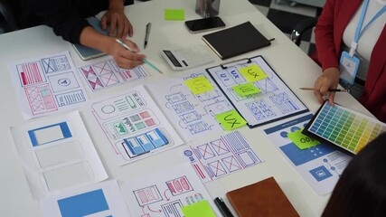 UX developer and ui designer brainstorming about mobile app interface wireframe design with customer breif and color code at office.